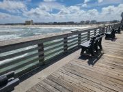 A view of pier handrail, ocean and beach